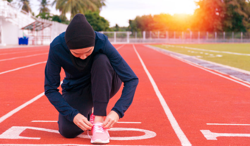 Ilustrasi - Seorang wanita tengah bersiap untuk berolahraga di sebuah lintasan lari. Foto: Shutterstock