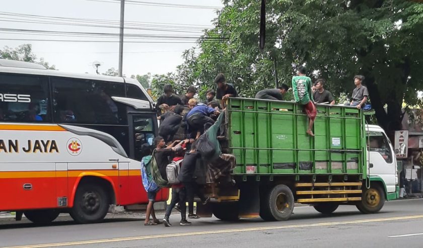 Berniat menumpang, beberapa anak memberhentikan Truk yang sedang melaju. Lalu naik ke bagian bak Truk yang kosong. Lokasi di Bakalan Balongbendo, Sabtu (23/1) siang