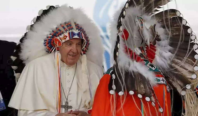 Kepala Wilton Littlechild dari kelompok penduduk asli Cree, menempatkan hiasan kepala bulu di kepala Paus.