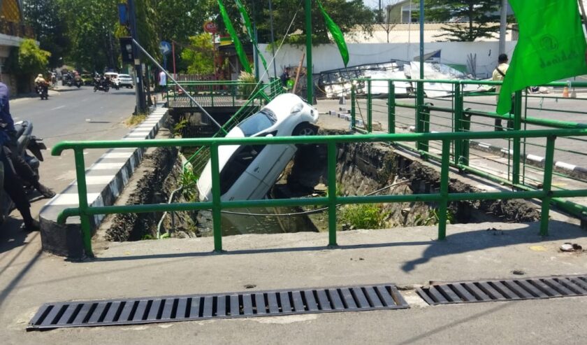 Mobil terperosok di parit di depan supermarket di Jl Arief Rahman Hakim Surabaya, Kamis (28/9/2023) siang.