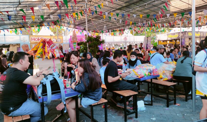 Pengunjung beristirahat dan menikmati makanan setelah berburu Snack di Pekan Raya Jatim (PRJ) pada Sabtu (21/10/2023). Foto: Feby Magang Suara Surabaya