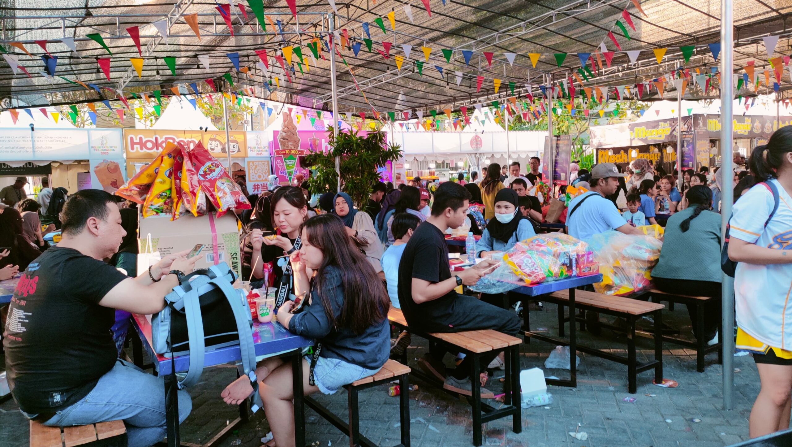 Pengunjung beristirahat dan menikmati makanan setelah berburu Snack di Pekan Raya Jatim (PRJ) pada Sabtu (21/10/2023). Foto: Feby Magang Suara Surabaya