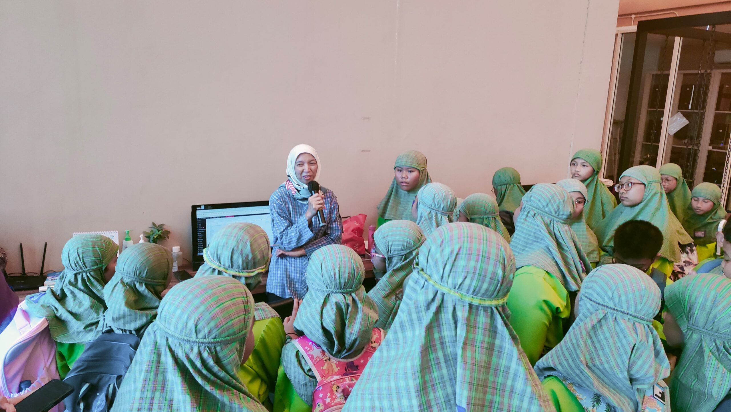 Iping Supingah redaktur new media saat menjelaskan kepada siswa dan siswi SDIK Mutiara Anak Sholeh terkait berita Suarasurabaya.net di Suara Surabaya Centre, Kamis (26/10/2023). Foto: Feby Magang Suarasurabaya.net 