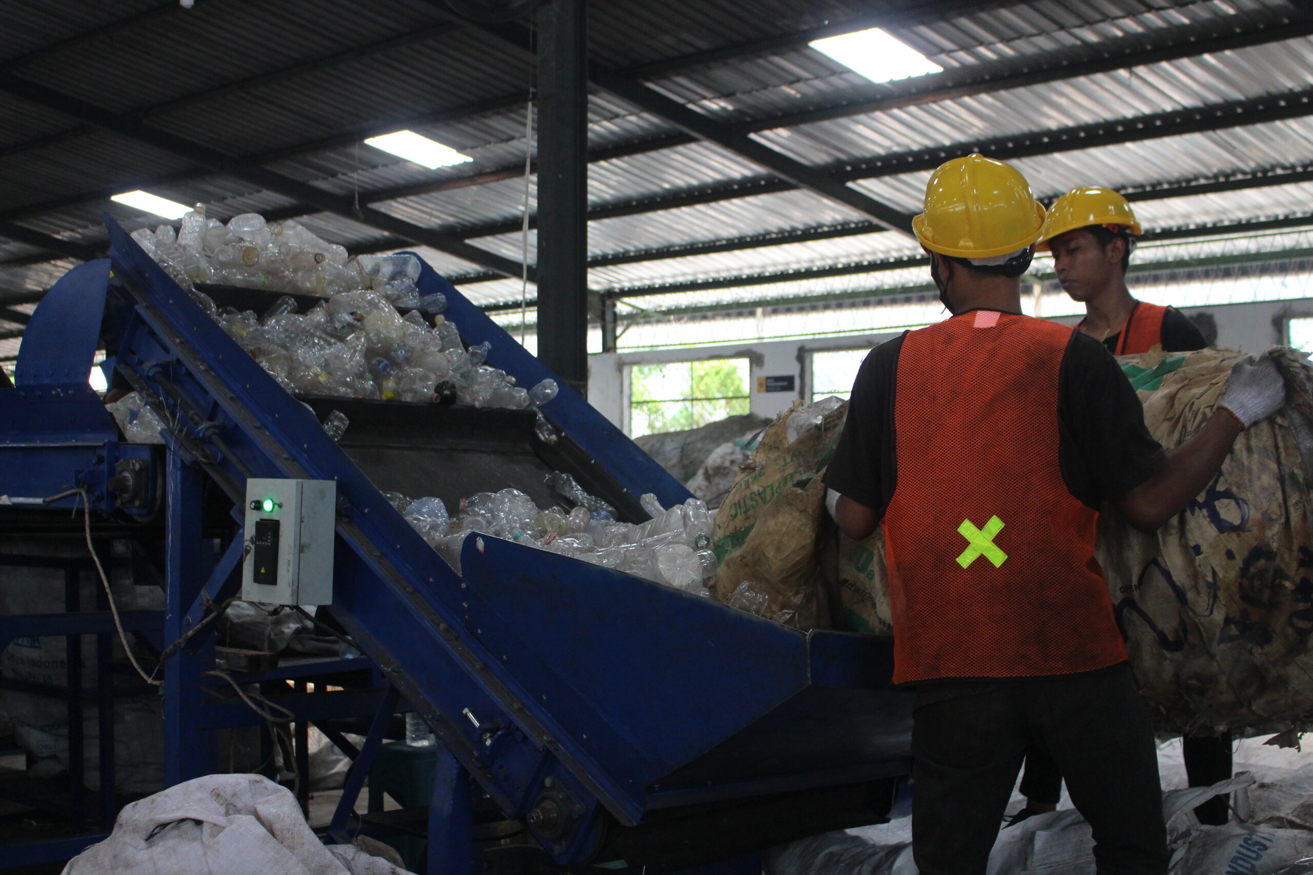 Proses masuknya botol plastik dalam Conveyor Belt Machine di Gedung KHI Surabaya, Driyorejo, Kabupaten Gresik, Sabtu (11/11/2023). Foto: Athalia magang suarasurabaya.net