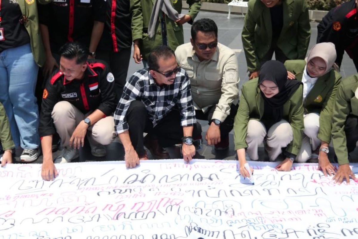 Wakil Ketua DPRD Kota Surabaya AH Thony bersama mahasiswa UPN Veteran Jatim menuliskan aksara Jawa pada kain putih yang dibentangkan di Balai Pemuda Surabaya, Selasa (31/10/2023), dalam upaya pelestarian budaya Jawa. Foto : Antara
