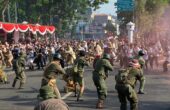 Atraksi pertempuran 10 November 1945 yang berlangsung di Jalan Pahlawan Kota Surabaya. Nampak puluhan orang memeragakan pertempuran setelah suara dentuman terdengar nyaring menandai dimulainya perang, Minggu (5/11/2023). Foto: Wildan suarasurabaya.net