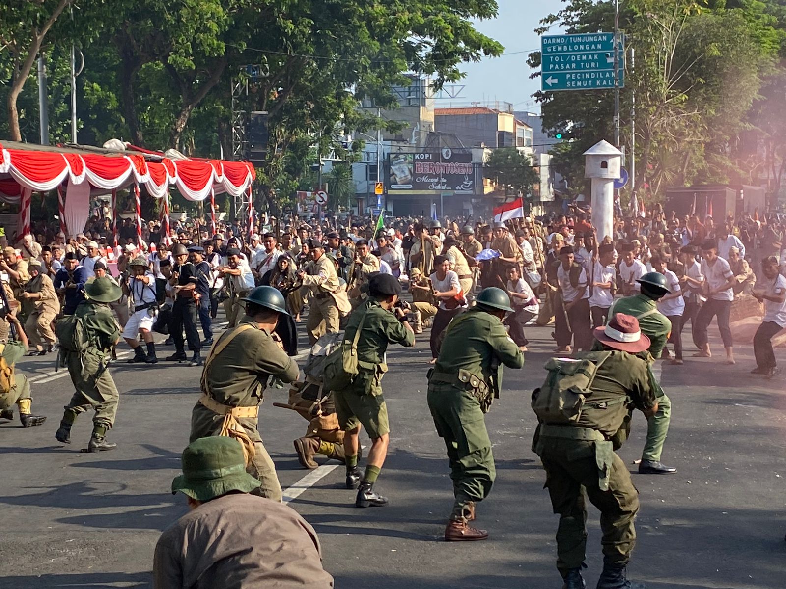 Atraksi pertempuran 10 November 1945 yang berlangsung di Jalan Pahlawan Kota Surabaya. Nampak puluhan orang memeragakan pertempuran setelah suara dentuman terdengar nyaring menandai dimulainya perang, Minggu (5/11/2023). Foto: Wildan suarasurabaya.net