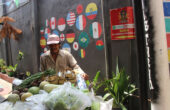 Pedagang sayur melewati jalanan yang dihiasi bendera berbagai negara dalam menyambut Piala Dunia U-17 2023 di RT 2, RW 9 Lemah Putro, Kampung Embong Kaliasin, Surabaya, Rabu (1/11/2023). Foto: Athalia magang suarasurabaya.net