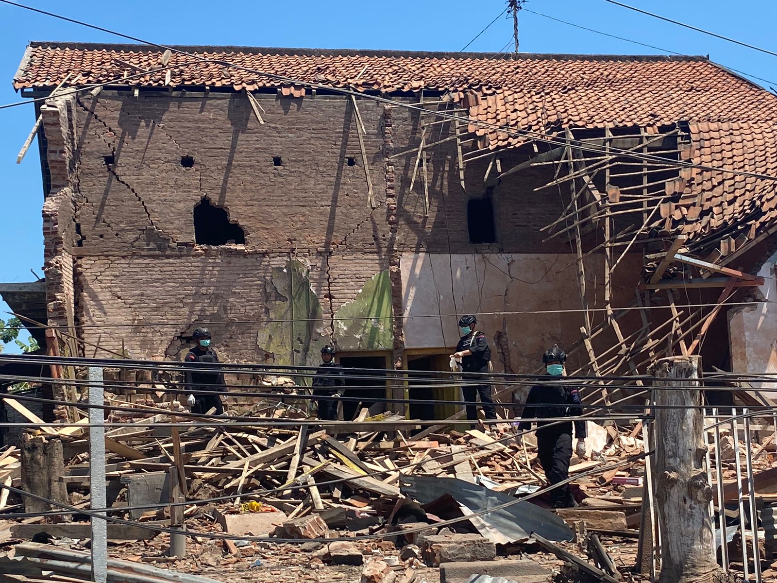 Tim gegana menyusuri bangunan rumah yang hancur terdampak ledakan di Jalan Komal, Kabupaten Bangkalan, Jumat (29/12/2023). Foto: Wildan suarasurabaya.net