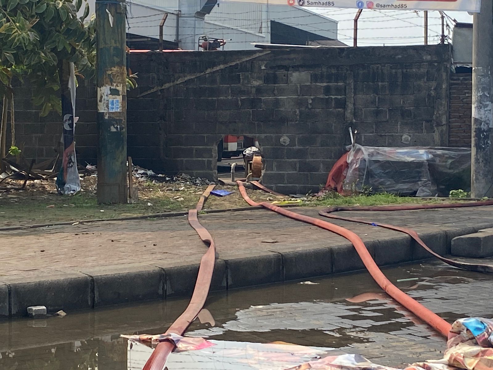 Petugas menjebol tembok gudang di sisi utara untuk menghubungkan air dengan armada penyedot di sungai supaya pasokan air terjaga, Jumat (8/12/2023). Foto: Wildan suarasurabaya.net