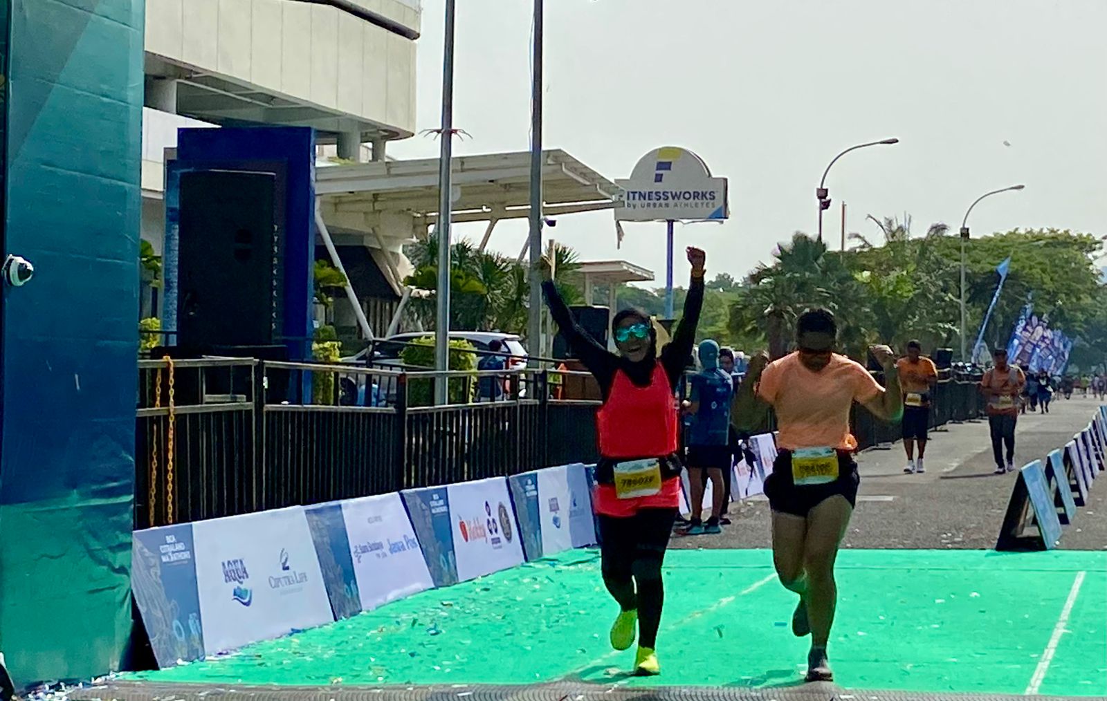 Dua perempuan peserta pelari Marathon BCA CITRALAND MARATHON 2023 melakukan selebrasi di depan garis finish, Minggu (10/12/2023). Foto: Wildan suarasurabaya.net