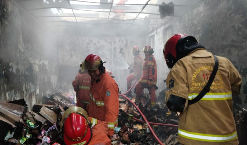 Petugas berusaha menjinakkan si jago merah yang melalap sebuah minimarket di Jalan Kalibutuh, Surabaya pada Senin (29/1/2024) sore. Foto: Command Center 112