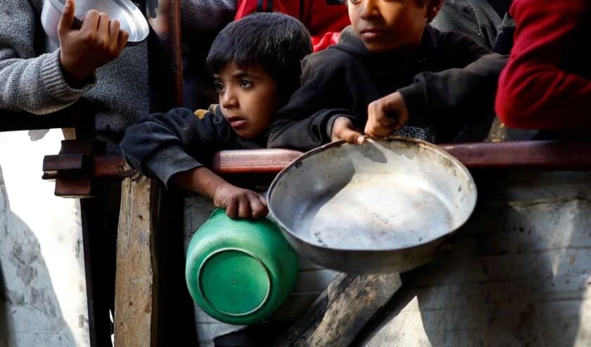 Warga Palestina menunggu untuk menerima makanan yang dimasak oleh dapur amal di tengah kekurangan pasokan makanan, saat konflik yang sedang berlangsung antara Israel dan kelompok Hamas, di Rafah di Jalur Gaza selatan, Jumat (16/2/2024). Foto: Reuters