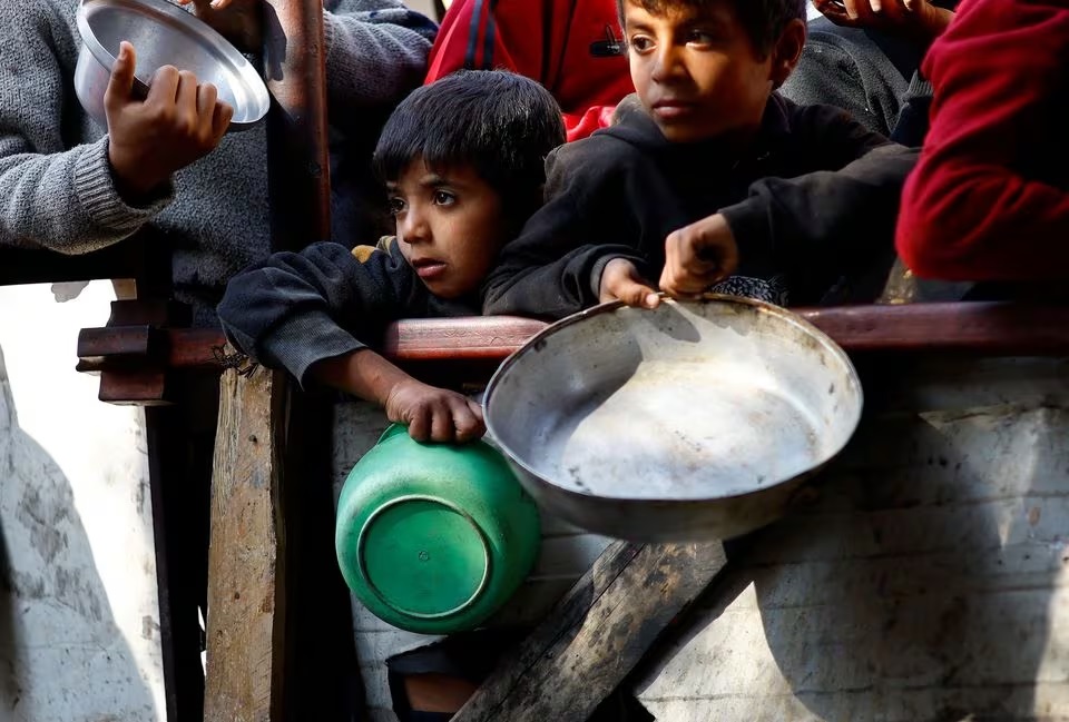 Warga Palestina menunggu untuk menerima makanan yang dimasak oleh dapur amal di tengah kekurangan pasokan makanan, saat konflik yang sedang berlangsung antara Israel dan kelompok Hamas, di Rafah di Jalur Gaza selatan, Jumat (16/2/2024). Foto: Reuters