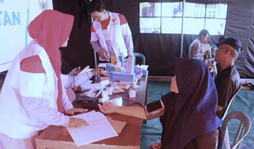 Petugas Puskesmas Karanganyar memeriksa kesehatan korban banjir yang mengungsi di posko darurat Kantor Desa Wonoketingal, Kecamatan Karanganyar, Kabupaten Demak, Jawa tengah, Selasa (20/2/2024). Foto: Antara