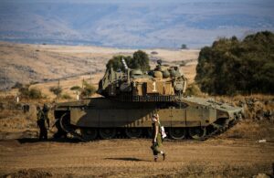 Seorang tentara Israel berjalan melewati sebuah tank di tengah meningkatnya ketegangan antara Israel dan Lebanon, terlihat dari perbatasan dengan Lebanon di Israel utara pada 14 Oktober 2023. Foto: Reuters