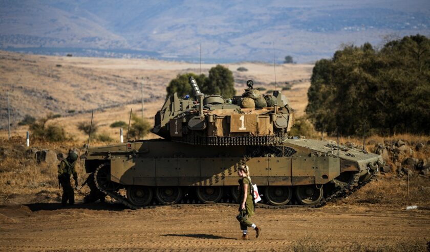 Seorang tentara Israel berjalan melewati sebuah tank di tengah meningkatnya ketegangan antara Israel dan Lebanon, terlihat dari perbatasan dengan Lebanon di Israel utara pada 14 Oktober 2023. Foto: Reuters