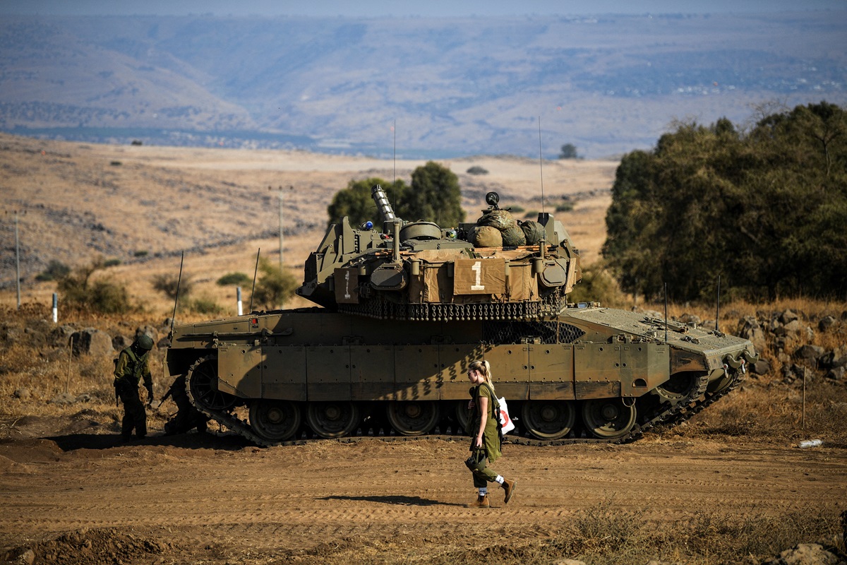 Seorang tentara Israel berjalan melewati sebuah tank di tengah meningkatnya ketegangan antara Israel dan Lebanon, terlihat dari perbatasan dengan Lebanon di Israel utara pada 14 Oktober 2023. Foto: Reuters