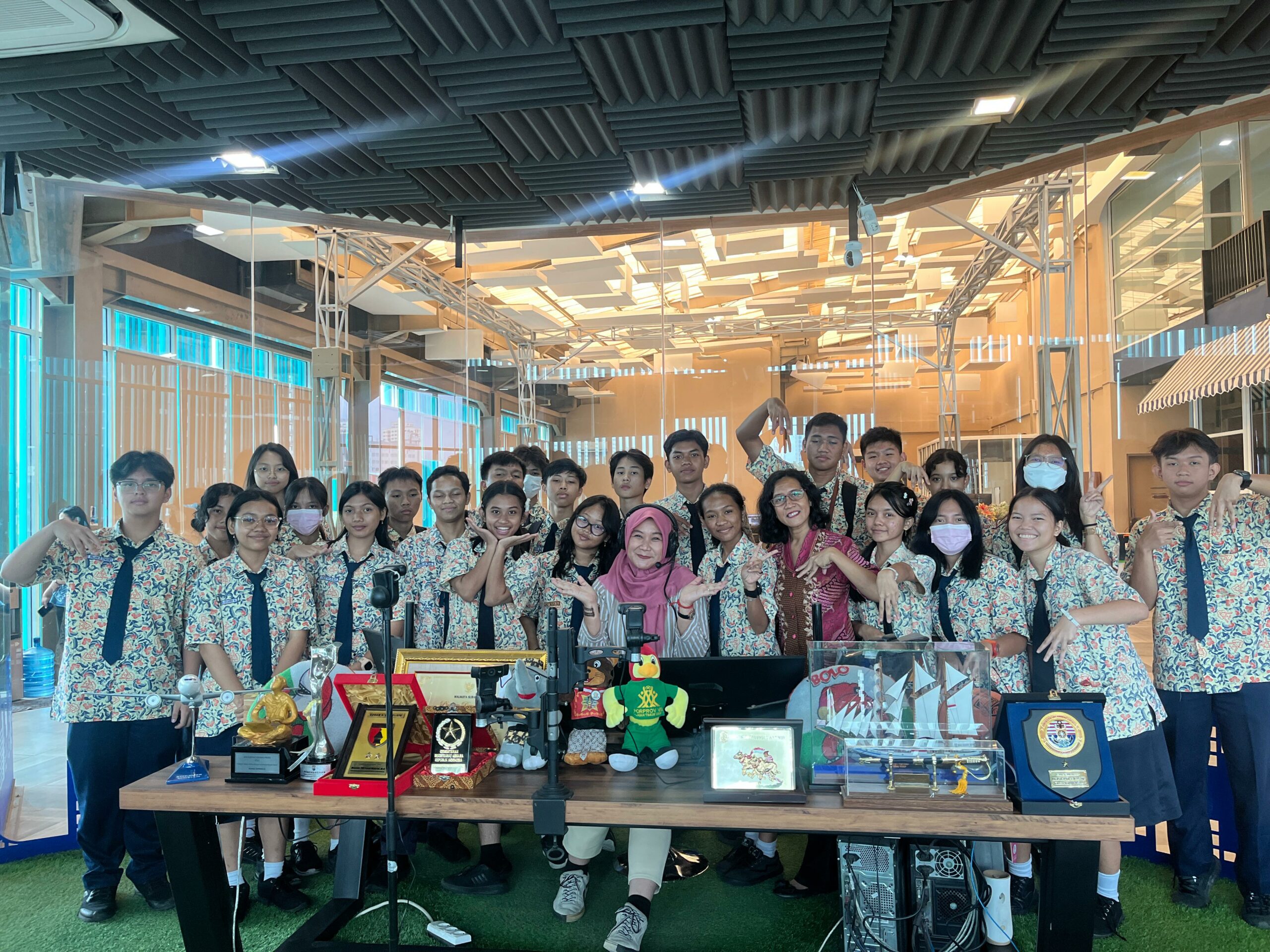 Aini Kusuma penyiar bersama siswa-siswi dan guru SMA Marge Surabaya berfoto bersama di ruang siaran Radio Suara Surabaya, Rabu (7/2/2024). Foto: Ikke magang suarasurabaya.net