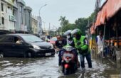 Seorang driver ojol harus menerobos genangan air di Jalan Raya Pepelegi sambil tetap mengangkut penumpangnya, Rabu (7/2/2024). Foto: Wildan suarasurabaya.net