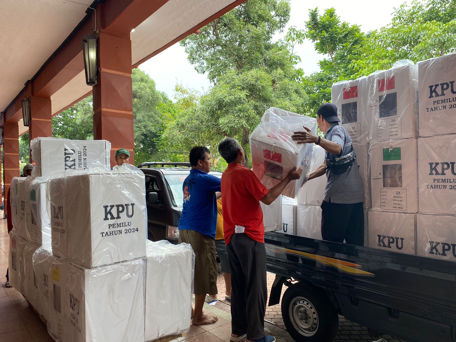 Petugas distribusi sibuk menata kotak suara untuk dipindahkan ke troli. Kemudian dibawa ke mobil pick up untuk dikirim ke kecamatan di Surabaya, Selasa (13/2/2024). Foto: Wildan suarasurabaya.net