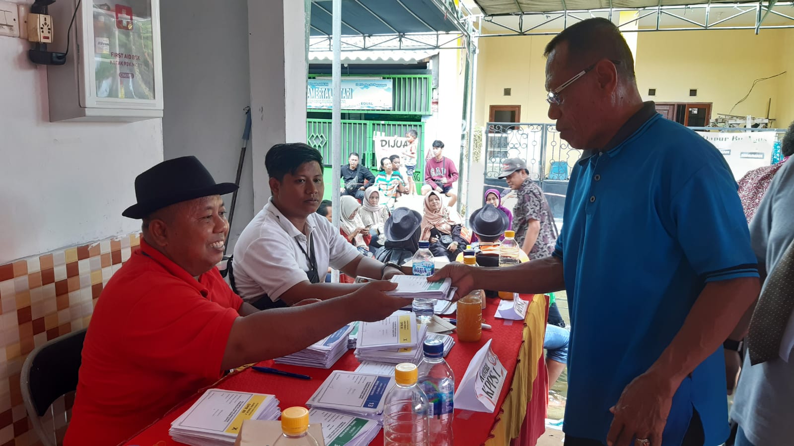 Saiful Ketua KPPS TPS 14 saat memberikan surat suara kepada warga di Balai RT 28 Desa Bringkang, Kecamatan Menganti, Kabupaten Gresik. Rabu (14/2/2024). Foto: Ikke Magang suarasurabaya.net
