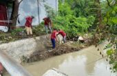 Petugas nampak membersihkan tumpukan ranting di sungai yang mengalir di dekat pemukiman Pakal Madya Barat, Minggu (18/2/2024). Foto: Wildan suarasurabaya.net