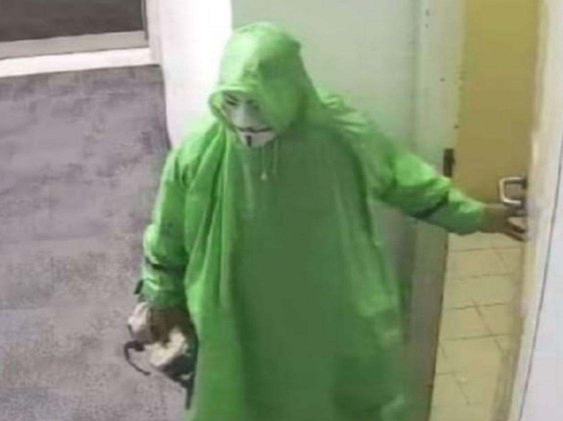 WH tersangka pencurian di kantor kawasan Kendangsari Surabaya sambil memakai topeng dan jas hujan warna hijau. Foto: Istimewa.