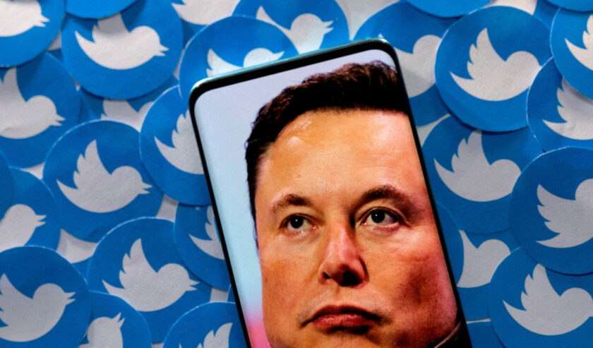 Ilustrasi gambar Elon Musk terlihat di smartphone yang ditempatkan pada cetakan logo Twitter. Foto: Reuters