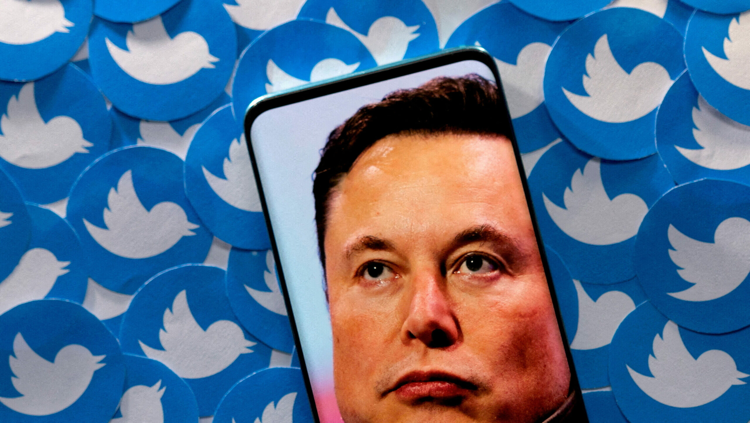 Ilustrasi gambar Elon Musk terlihat di smartphone yang ditempatkan pada cetakan logo Twitter. Foto: Reuters