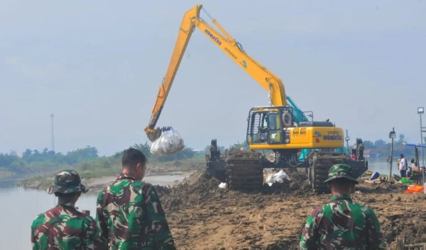 Pekerja mengoperasikan alat berat saat melakukan perbaikan tanggul Sungai Wulan yang jebol dan berdampak banjir di Desa Ketanjung, Karanganyar, Demak, Jawa Tengah, Jumat (22/3/2024). Foto: Antara