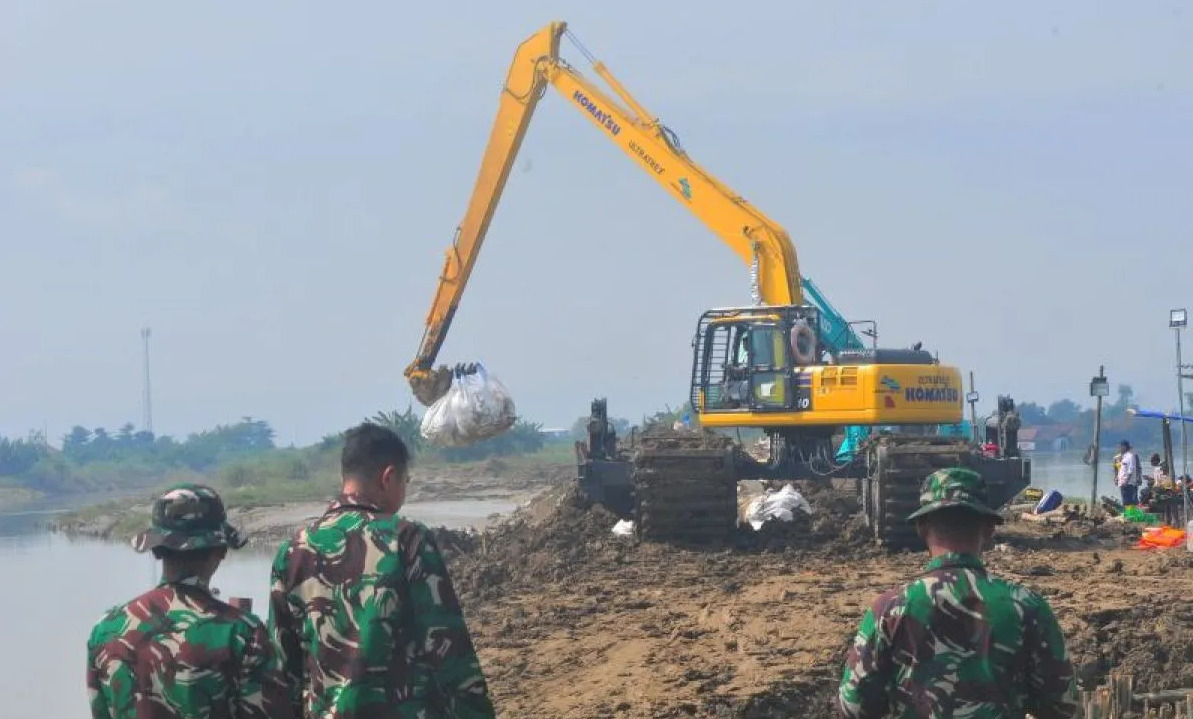 Pekerja mengoperasikan alat berat saat melakukan perbaikan tanggul Sungai Wulan yang jebol dan berdampak banjir di Desa Ketanjung, Karanganyar, Demak, Jawa Tengah, Jumat (22/3/2024). Foto: Antara