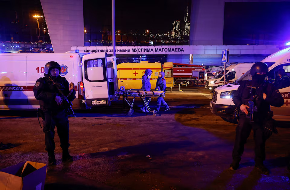 Petugas penegak hukum Rusia berjaga-jaga di dekat lokasi konser Crocus City Hall yang terbakar menyusul insiden penembakan, di luar Moskow, Rusia pada Jumat (22/3/2024). Foto: Reuters