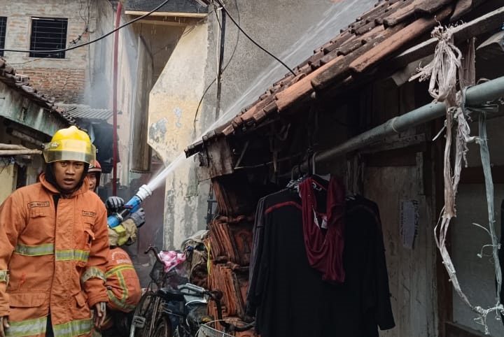 Petugas berupaya memadamkan api yang melalap sebuah rumah di Jalan Kedungdoro VI, Surabaya pada Selasa (26/3/2024) pagi. Foto: Command Center 112