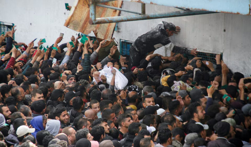 Warga Palestina berkumpul untuk menerima bantuan di luar gudang UNRWA ketika penduduk Gaza menghadapi krisis kelaparan, di Kota Gaza, Senin (18/3/2024). Foto: Reuters