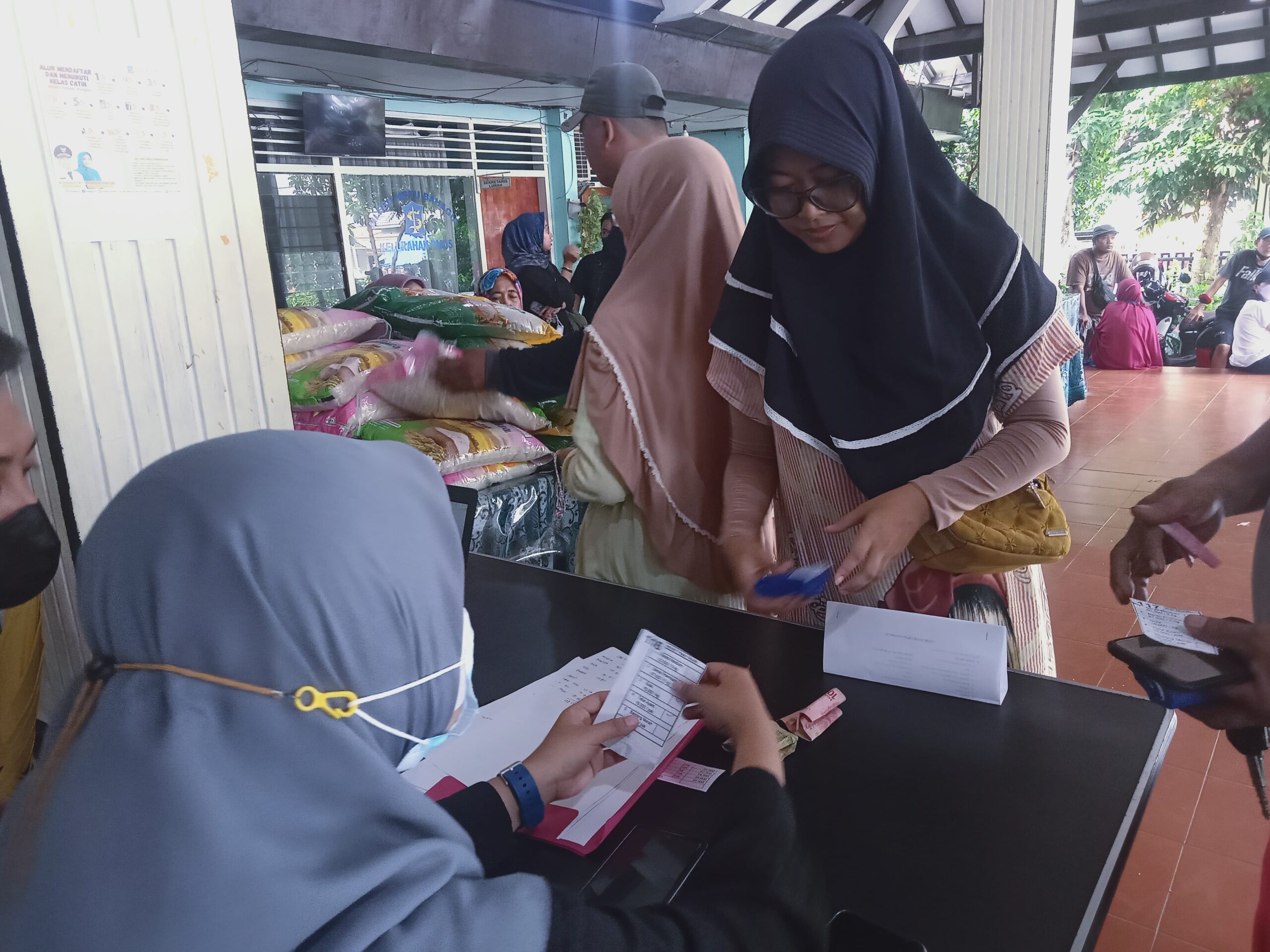 Warga membayar bahan pokok di Pasar Murah Kelurahan Pakis, Kecamatan Sawahan, Kota Surabaya, Selasa (12/3/2024). Foto: Dani magang suarasurabaya.net