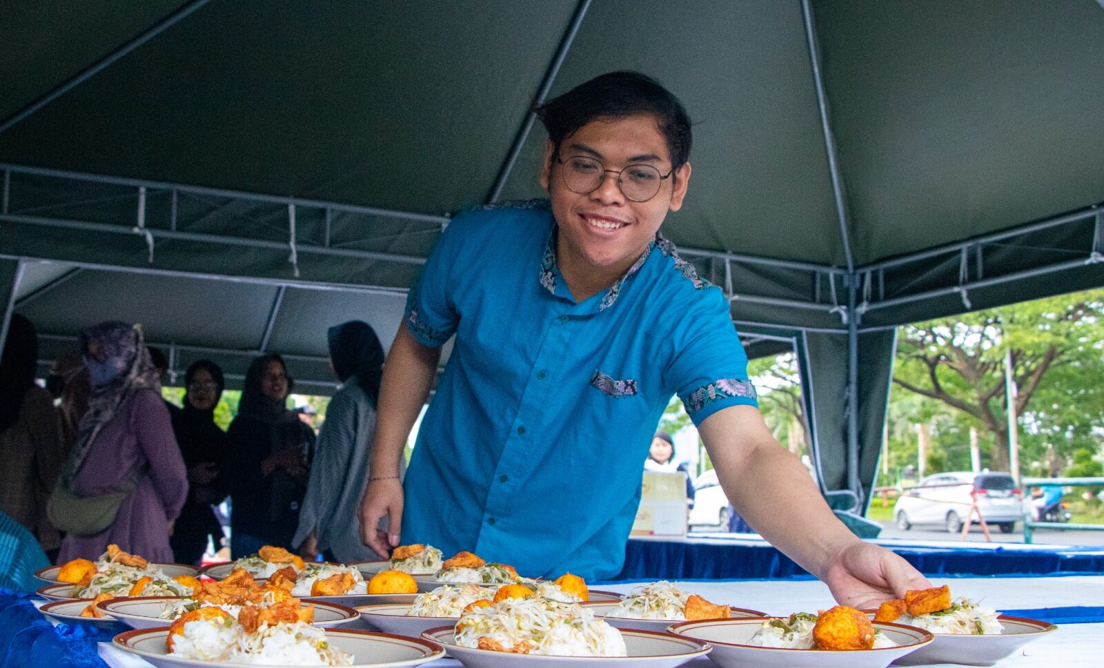 Salah seorang mahasiswa yang mengambil makanan dalam acara buka puasa bersama dan pembagian takjil gratis, pada Jumat (15/3/2024) di depan gerbang utama UNESA Kampus 2 Lidah Wetan, Surabaya. Foto: Humas UNESA