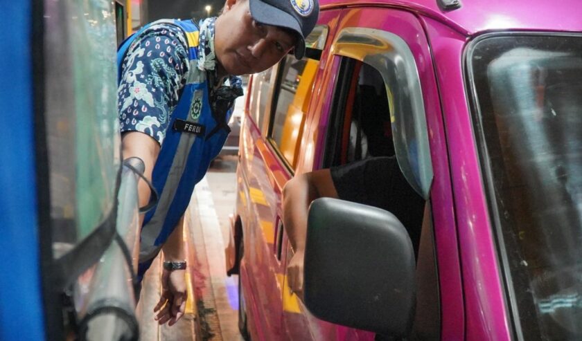 Petugas membantu pengendara melakukan pembayaran tarif tol menggunakan saldo elektronik.