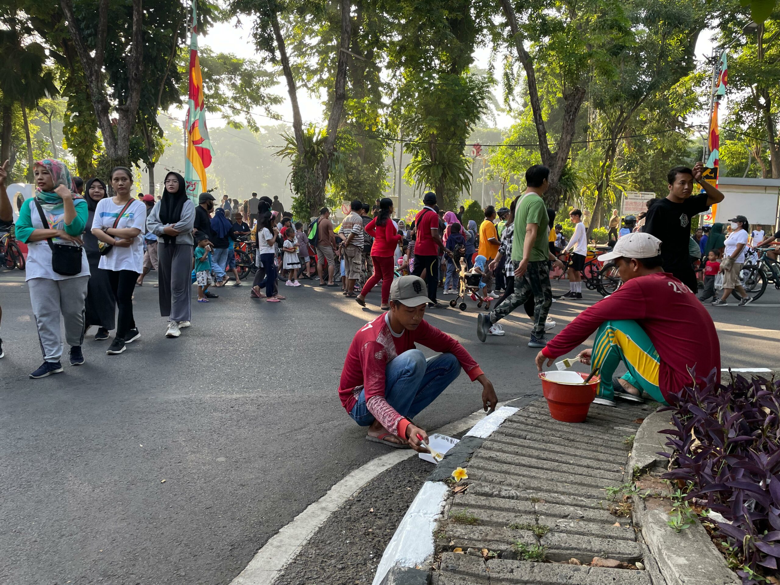 Petugas kebersihan Taman Bungkul yang ikut mengecat trotoar jalur tengah di, Minggu (12/5/2024). Foto: Firman magang suarasurabaya.net