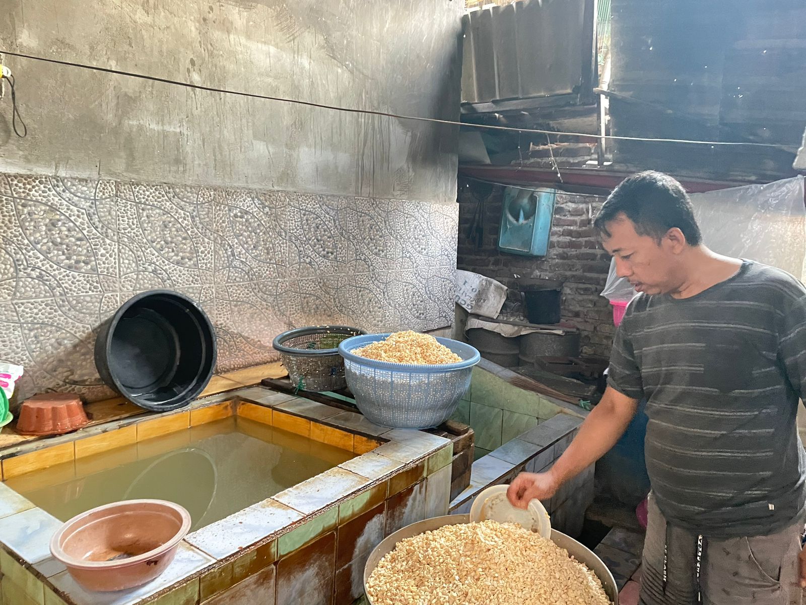 Ghofur saat melakukan proses perendaman kedelai dengan ragi di Kammpung Tempe Surabaya, Rabu (8/5/2024). Foto: Firman magang suarasurabaya.net